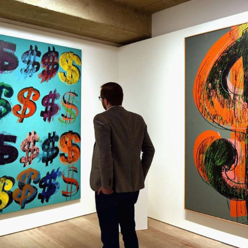 Man looking at painting of dollar signs in a art gallery