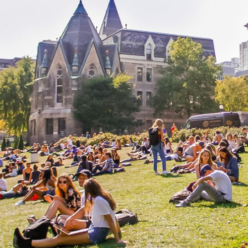 Students relaxing in the grass in front of university